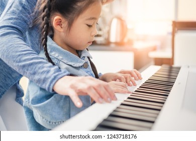 Asian young pianist teacher teaching girl kid student to play piano, music education concept