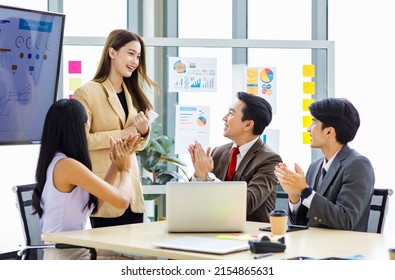 Asian young pretty professional successful businesswoman staff standing greeting say thank you when finishing presentation while male and female colleagues clapping hands together admire compliment.