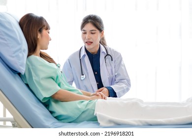 Asian Young Professional Female Doctor In White Lab Coat With Stethoscope Sitting Holding Human Spine Skeleton Model Showing Explaining Supporting Comforting Patient Laying Down On Bed In Ward Room.