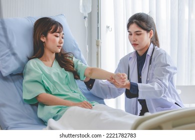 Asian Young Professional Female Practitioner Doctor In White Lab Coat With Stethoscope Holding Touching Checking Monitoring Patient Injury Arm And Muscle While Laying Down On Bed In Hospital Wardroom.