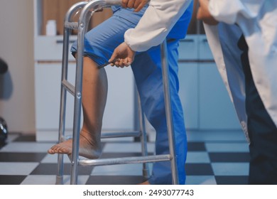 Asian young professional successful friendly female nurse in blue hospital uniform helping supporting physical therapy senior old pensioner unhealthy injury woman patient walking via four legs walker. - Powered by Shutterstock