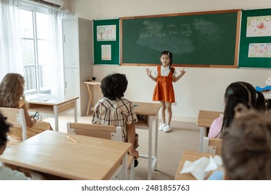 Asian young schoolgirl student dancing in front of classroom at school. Adorable little kid feeling happy and enjoy presenting learning lesson, perform a show with teacher at elementary kindergarten. - Powered by Shutterstock