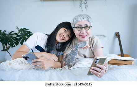 Asian Young And Senior Women Are Using Smartphone. Daughter Is Helping Mother Having Fun Staying At Home.Elder Using Mobile Phone,Social Network,Family,Technology Concept.