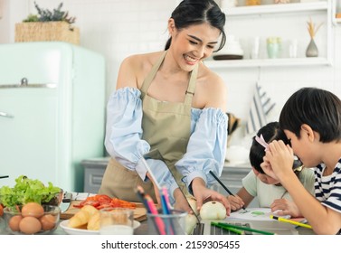 Asian Young Single Mother Making Food While Taking Care Child In Kitchen. Home School And Single Mother Concept.