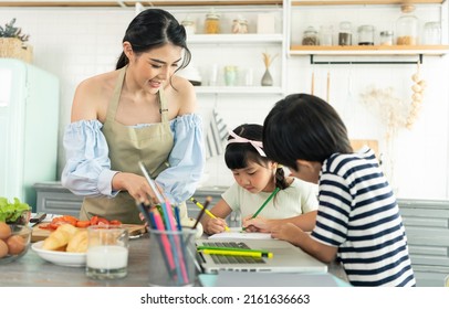 Asian Young Single Mother Making Food While Taking Care Child In Kitchen. Home School And Single Mother Concept.