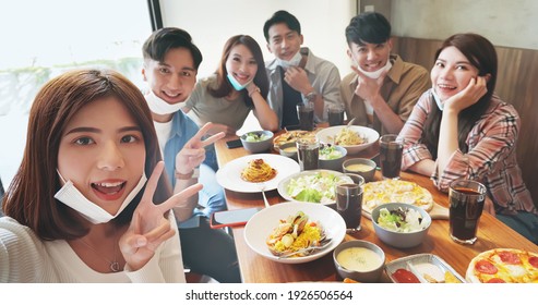 Asian Young Six Friends Wearing Face Mask On Chin Taking Selfie In Restaurant Happily