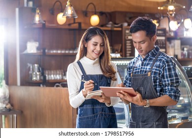 Asian Young Small Business Owner Discussing And Coaching Job Together With Colleague In Domestic Coffee Shop, Entrepreneur And Startup, Using Technology Laptop And Lecture, Business Partner Concept