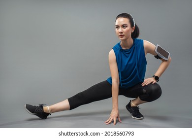 Asian young sportswoman stretching and preparing to exercise on grey background. Beautiful woman in sportswear stretching.