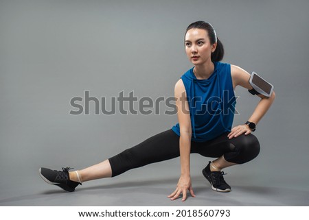Asian young sportswoman stretching and preparing to exercise on grey background. Beautiful woman in sportswear stretching. 商業照片 © 