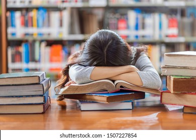 Asian young Student in casual suit reading and sleeping on the wooden table with various book in library of university or colleage over the book shelf, Back to school concept - Powered by Shutterstock