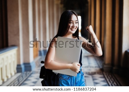Asian Young Students or Start up Adolescents celebrate hands up after watching exam results in laptop, happy joy of accomplishing successful goal activities with expression positive emotion on campus