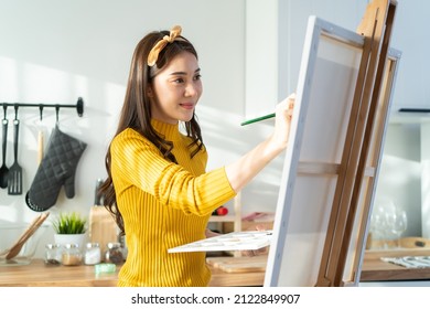 Asian young talented woman artist coloring on painting board in house. Attractive beautiful female draw art picture, creating artwork with watercolor paint and brush enjoy creativity activity at home. - Powered by Shutterstock