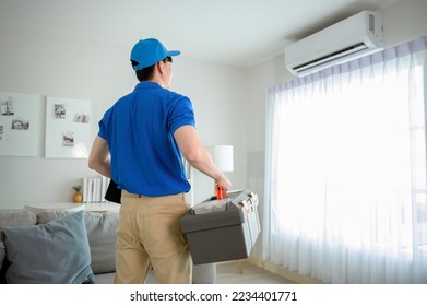 An Asian young Technician service man wearing blue uniform checking ,  cleaning air conditioner in home - Shutterstock ID 2234401771