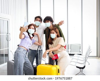 Asian Young Tourist Friend Group Wearing Face Mask To Prevent Coronavirus Infection Using Mobile Phone For Taking Selfie Photos During Waiting Airline Flight At Airport, New Normal Travel Concept.