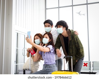 Asian Young Tourist Friend Group Wearing Face Mask To Prevent Coronavirus Infection Using Mobile Phone For Taking Selfie Photos At Airport Terminal, Social Distancing And New Normal Travel Concept.