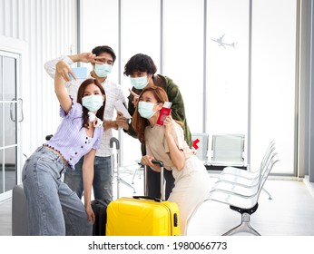 Asian Young Tourist Friend Group Wearing Face Mask To Prevent Coronavirus Infection Using Mobile Phone For Taking Selfie Photos During Waiting Airline Flight At Airport, New Normal Travel Concept.