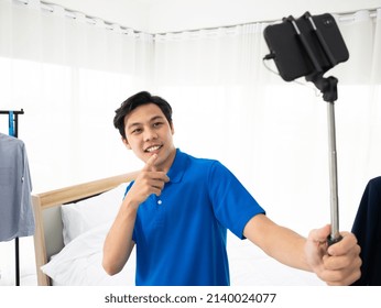 Asian Young Vlogger Use Selfie Stick To Record Live While Finger Point At Smartphone For Promote Renovate New Home On Social Media