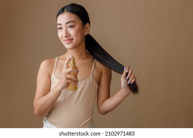 Asian Young Woman Applying Hair Spray On Her Ponytail