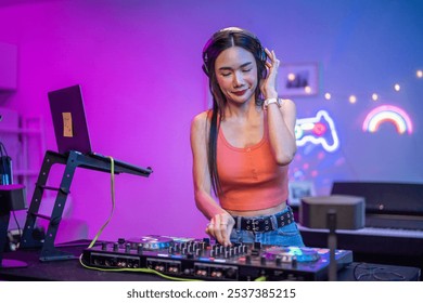 Asian young woman artist DJ mixing and scratching music mixer controller. Attractive female musician DJ having fun mixing music on console touching buttons and playing electronic music at neon party. - Powered by Shutterstock