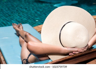 Asian Young  Woman In Big Hat Taking Sunbath At Swimming Pool Poolside Blue Water