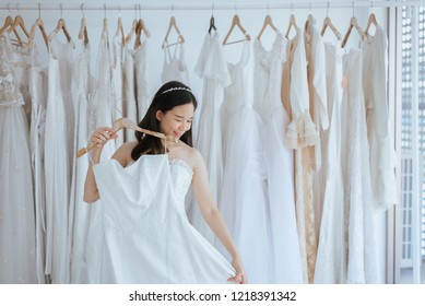 Asian young woman bride trying on wedding dress at modern wedding,Happy and smiling,ฺBride dressing,Gown dress - Powered by Shutterstock