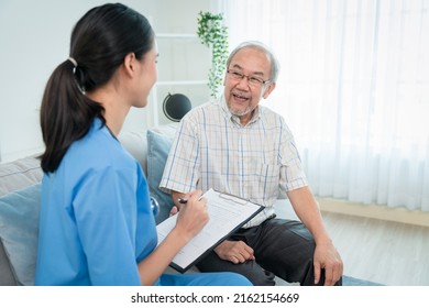 Asian Young Woman Caregiver Doctor Give Consultation And Writing Problem Of Elderly Man Patient In Room During Home Visit