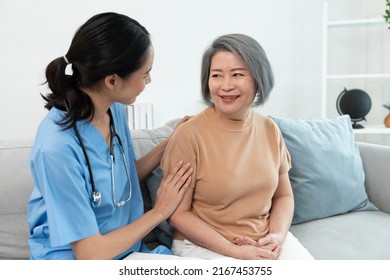 Asian young woman caregiver nurse talking with grandmother sitting on sofa in living room during home visit.Young female psychological doctor give help take care of elderly woman patients.