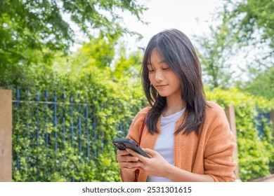 Asian young woman chatting on cellphone smiling laughing while walking outdoors in city. Teenage girl use smartphone communicate online texting while traveling outside in downtown. - Powered by Shutterstock