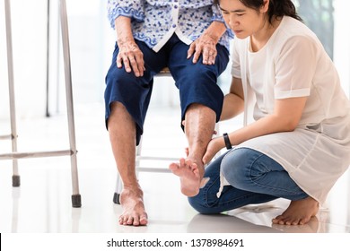 Asian young woman checking knee of elderly woman at home,senior woman receiving massage by female physic therapist of her leg due to injury