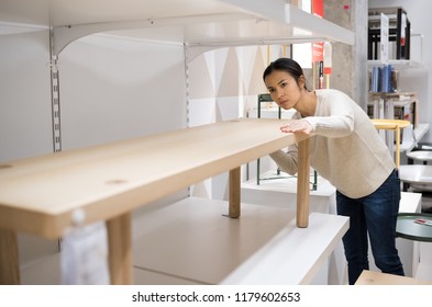 asian young woman choosing the right furniture for her apartment in a modern home furnishings store