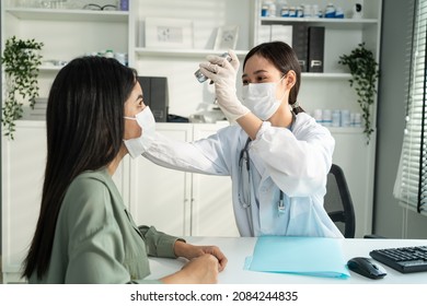 Asian Young Woman Doctor Using Flashlight On Patient's Eye In Hospital. Attractive Specialist Physician Wear Mask, Examining And Checking Eyesight For Lady In Clinic. Medical Insurance Service Concept