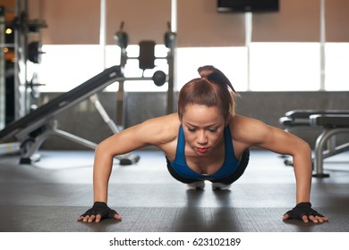 Asian young woman doing push-ups in gym