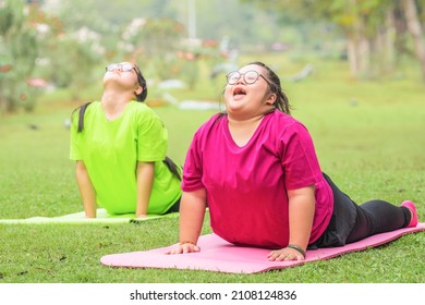 asian young woman with down syndrome or autism with friend exercising and doing yoga outdoors in park together - Shutterstock ID 2108124836
