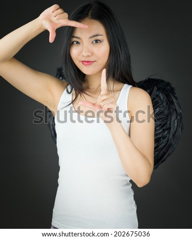 Asian young woman dressed up as an angel making frame with fingers
