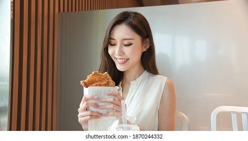 asian young woman drink bubble tea and eat fried chicken chop in the restaurant