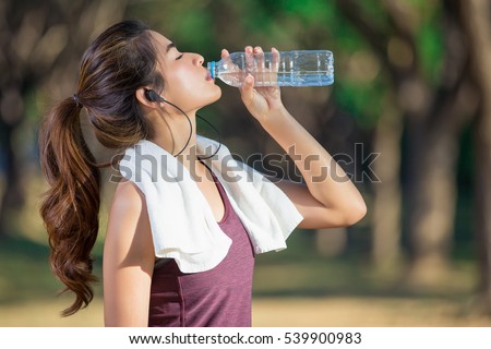 Asian young woman drinking water after jogging,healty and sport concept.