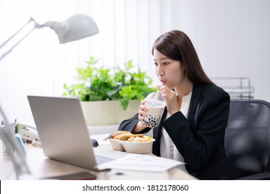 Asian Young Woman Eat Her Lunch And Tapioca Ball Tea While She Is Working In The Office