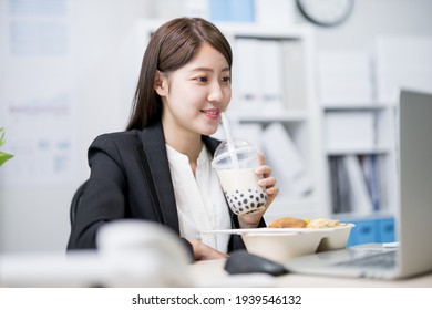 Asian Young Woman Eat Her Lunch And Tapioca Ball Tea While Working In The Office