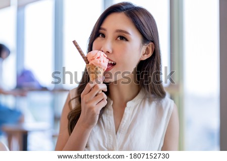 asian young woman eat ice cream dessert in waffle cone at restaurant