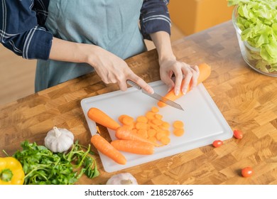 Asian young woman, girl or housewife hand using knife, cutting carrots on  board, on wooden table in kitchen home, preparing ingredient, recipe fresh vegetables for cooking meal. Healthy food people. - Powered by Shutterstock