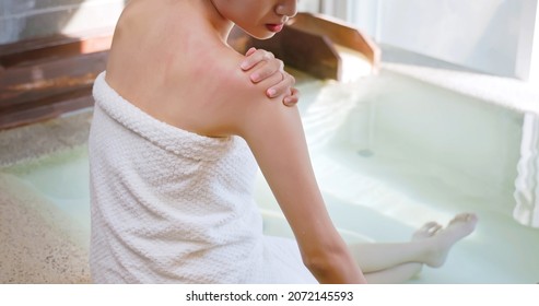 asian young woman has dry skin and scratches her shoulder while she sitting in hot spring