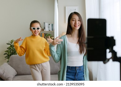 Asian young woman with her friend tiktoker created her dancing video by smartphone camera together. To share video to social media application