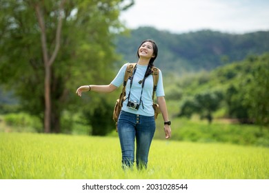 Asian Young Woman Holding Camera And Standing In The Jungle Adventure.  Tourism For Destination And Leisure Trips For Education And Relax In Nature Park.  Travel Vacations And Lifestyle Concept