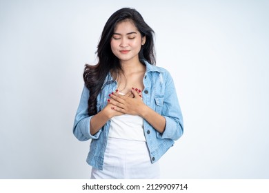 Asian Young Woman Holding Chest While Feeling Relieved