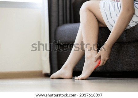 Asian young woman holding heel,symptom of Plantar Fasciitis,inflammation of the fascia of muscle,massage foot with her hand,relieve muscle fatigue,pain and stiffness in sole of the foot and ankle bone
