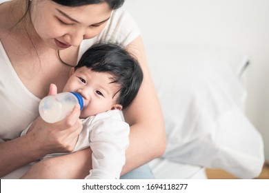 Asian Young Woman Hug, Feed Milk To Cute Infant Baby Boy. Son Happy To Stay And Sleep In Mom Warm Embrace. Infant Drink Nutrition Food From Mom. Mother Child Relationship For Kid Development Concept.