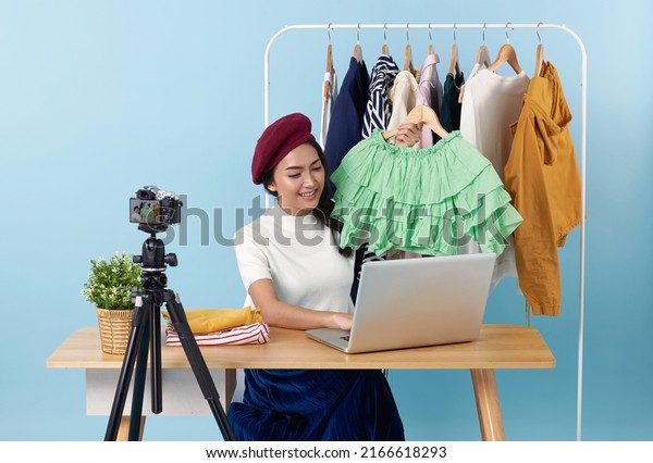 Asian young woman live\
streaming showing clothes in front of camera for sale fashion\
clothing is blogger presenting for social people.Her is influencer\
in social online.