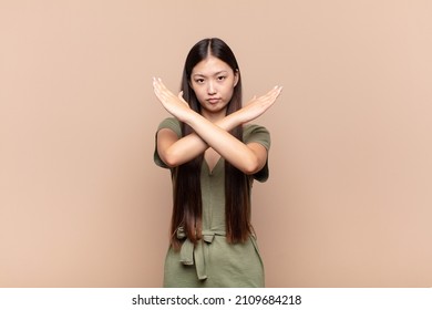 asian young woman looking annoyed and sick of your attitude, saying enough! hands crossed up front, telling you to stop - Shutterstock ID 2109684218