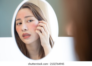 Asian Young Woman Looking Face Skin In The Mirror Have A Red Rash On Her Face From Cosmetic Allergy