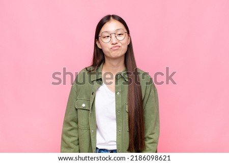 asian young woman looking goofy and funny with a silly cross-eyed expression, joking and fooling around